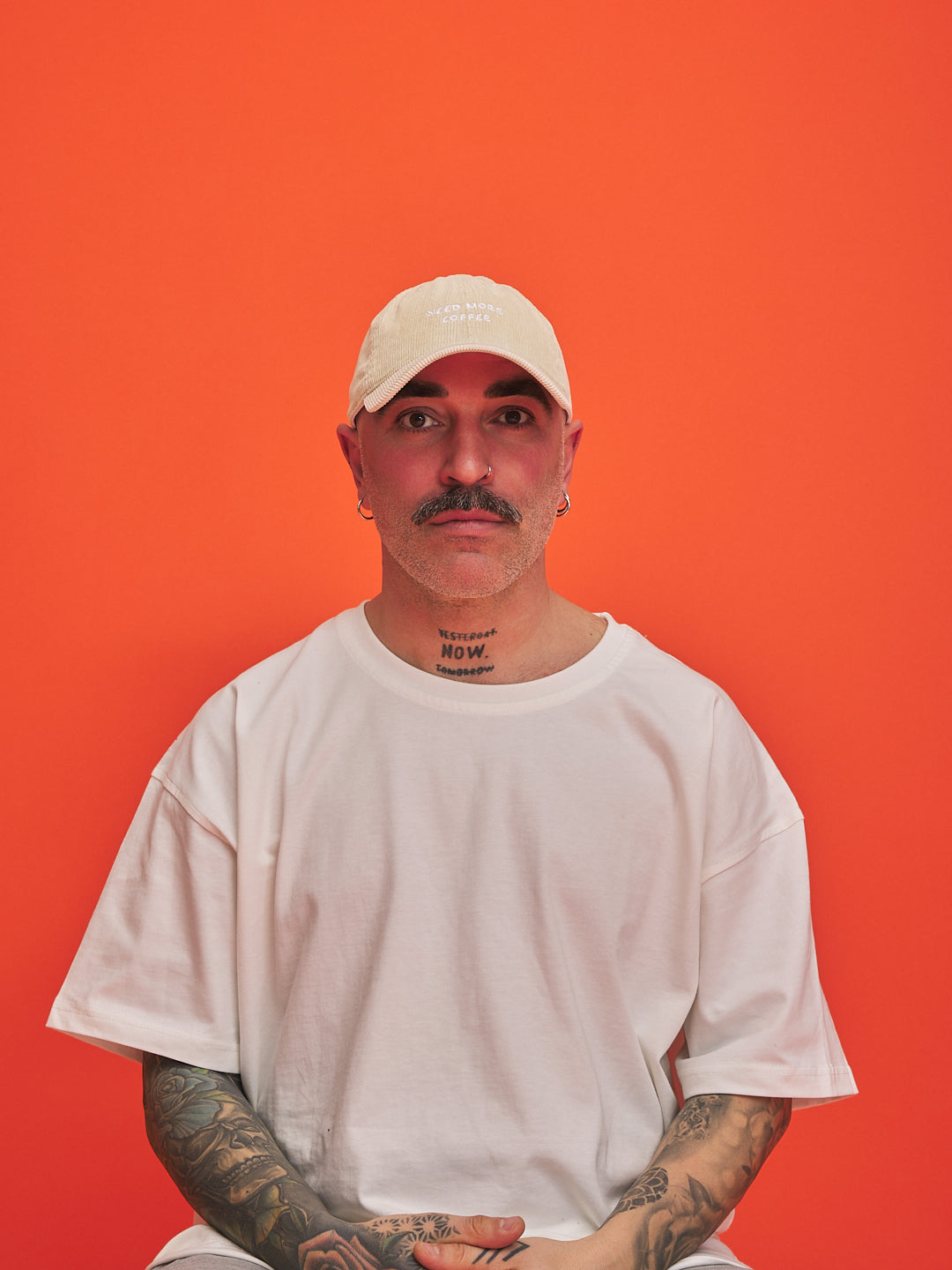 Person wearing a cream cap and white t-shirt against an orange background