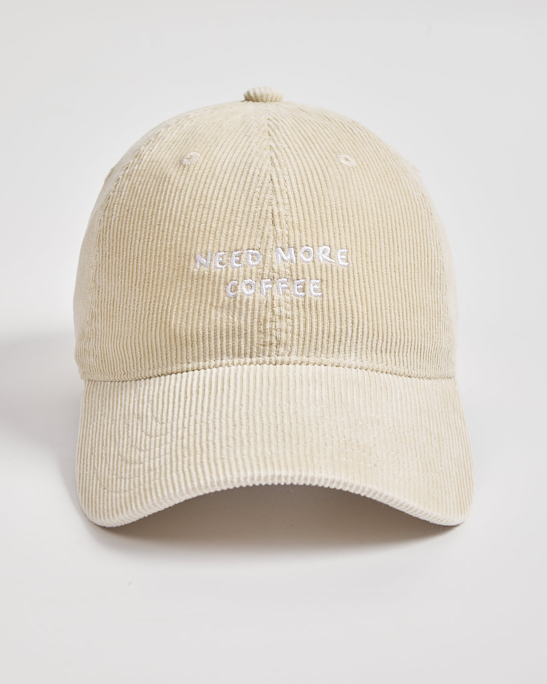 Cream cap with 'Need More Coffee' text on a light gray background