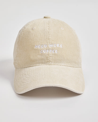 Cream cap with 'Need More Coffee' text on a light gray background