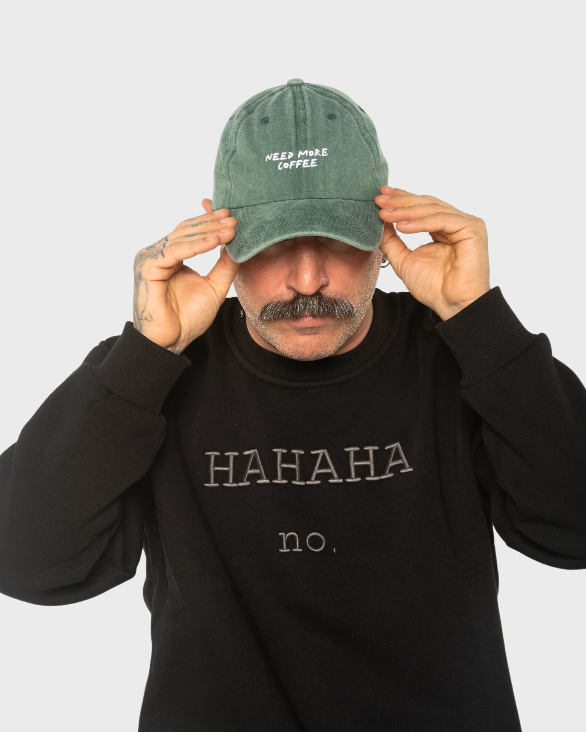 A man wearing the Need More Coffee Dark Green Washed Cap