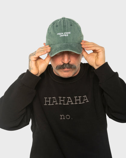 A man wearing the Need More Coffee Dark Green Washed Cap