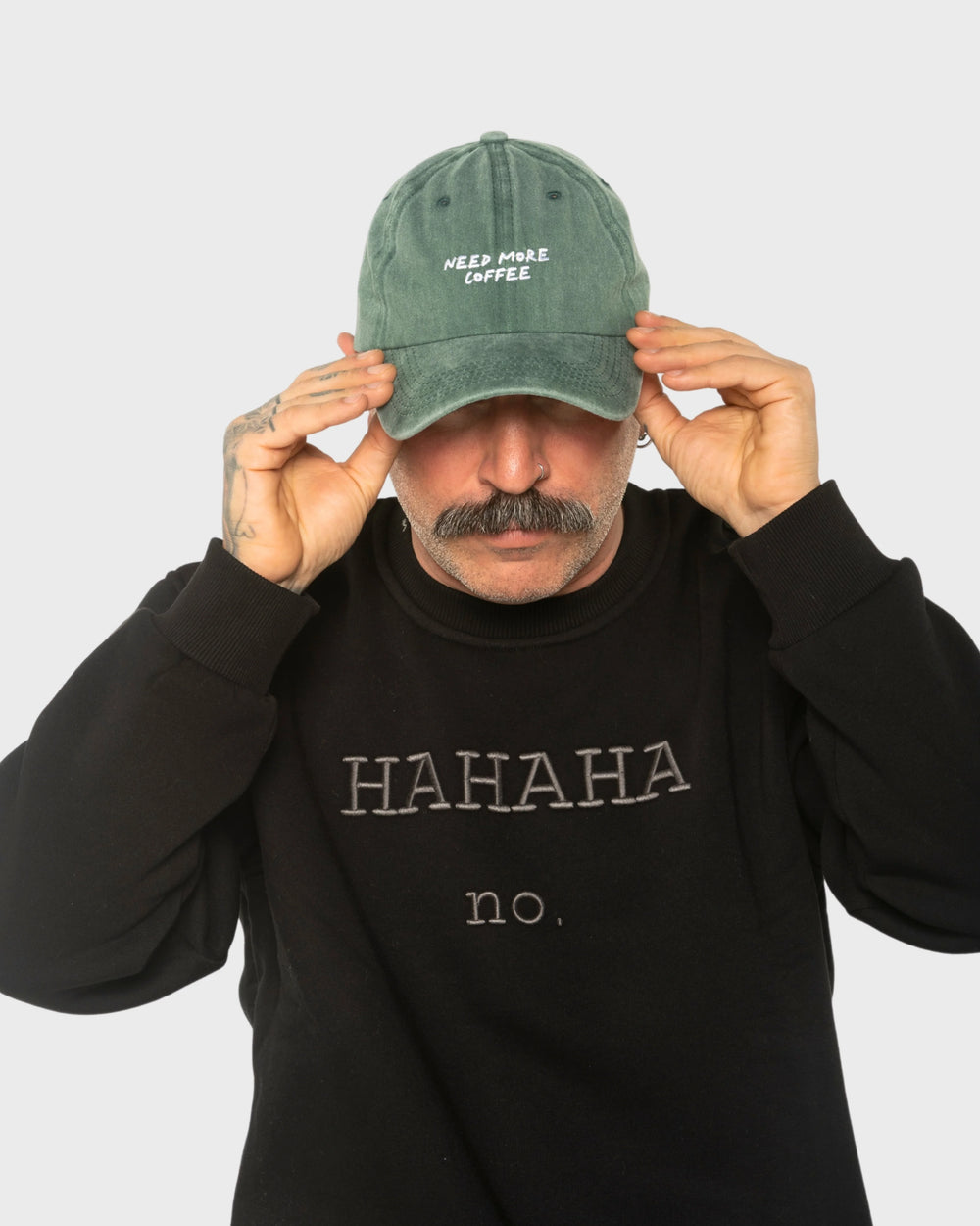 A man wearing the Need More Coffee Dark Green Washed Cap