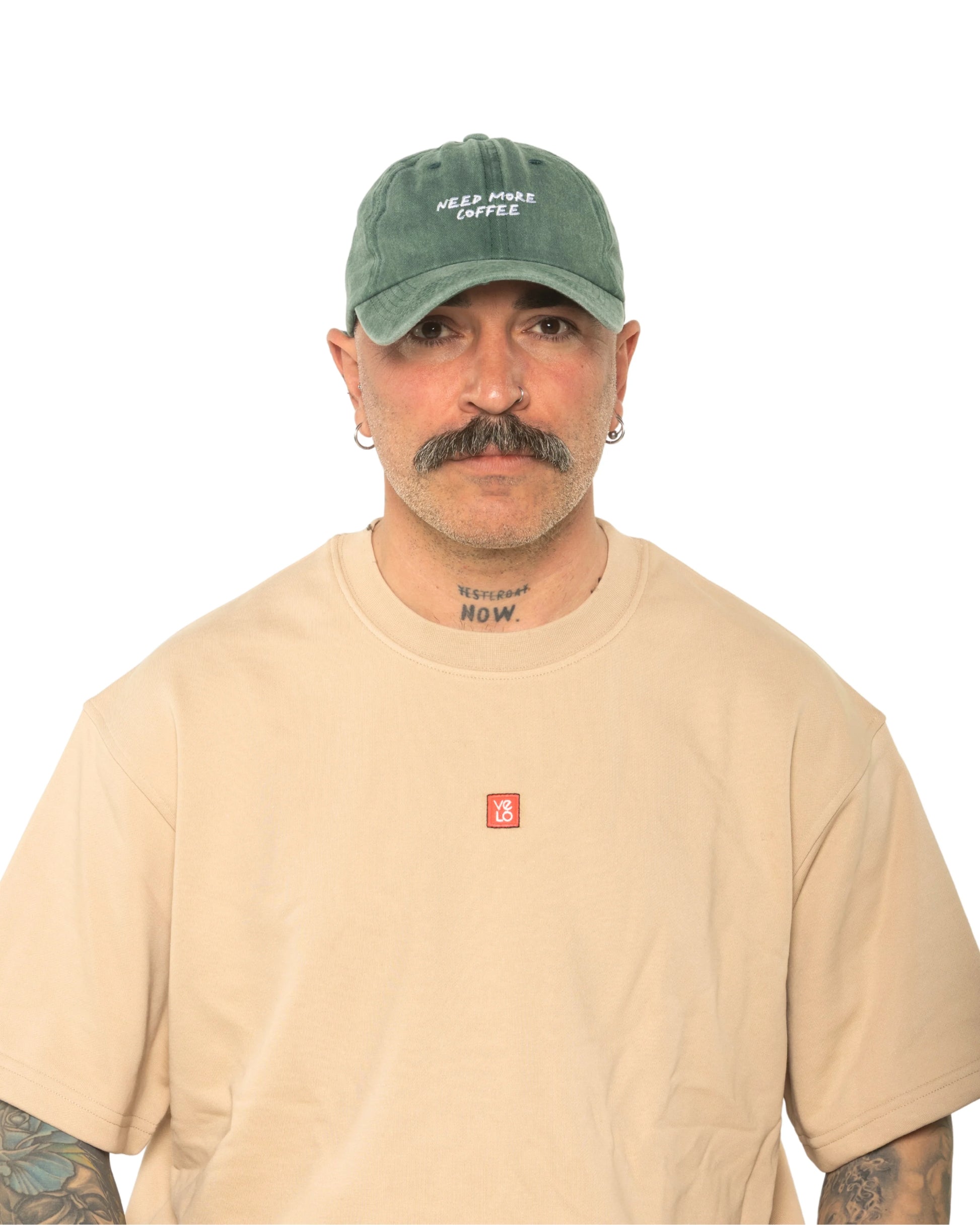 A man wearing the Need More Coffee Dark Green Washed Cap