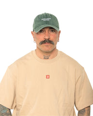 A man wearing the Need More Coffee Dark Green Washed Cap