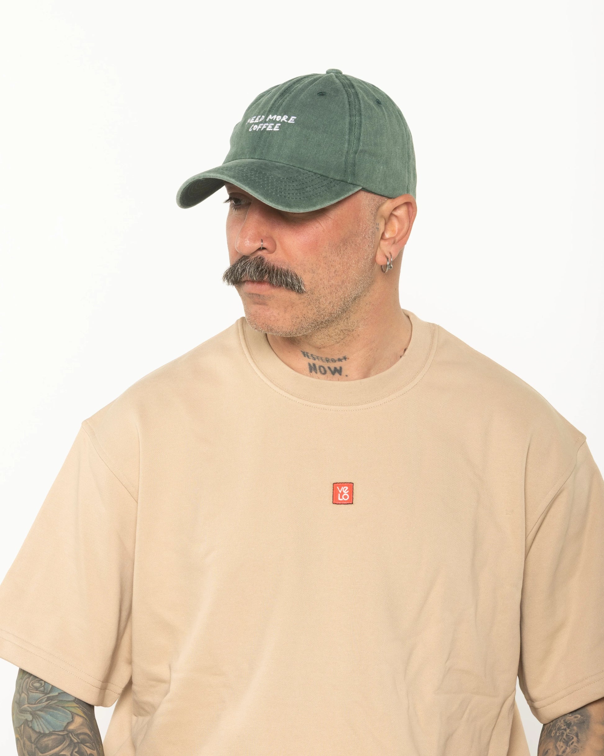 A man wearing the Need More Coffee Dark Green Washed Cap