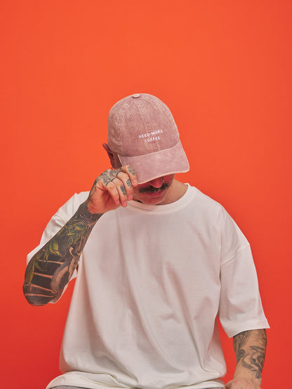 Person wearing a pink cap and white t-shirt against an orange background