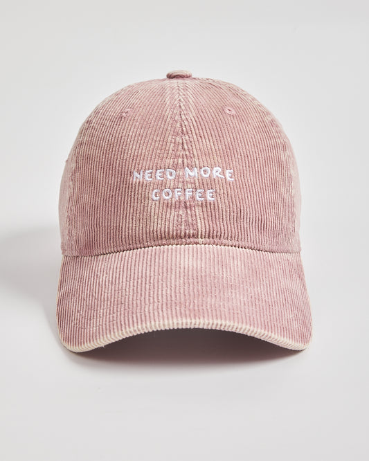 Pink corduroy cap with 'Need More Coffee' text on a light gray background