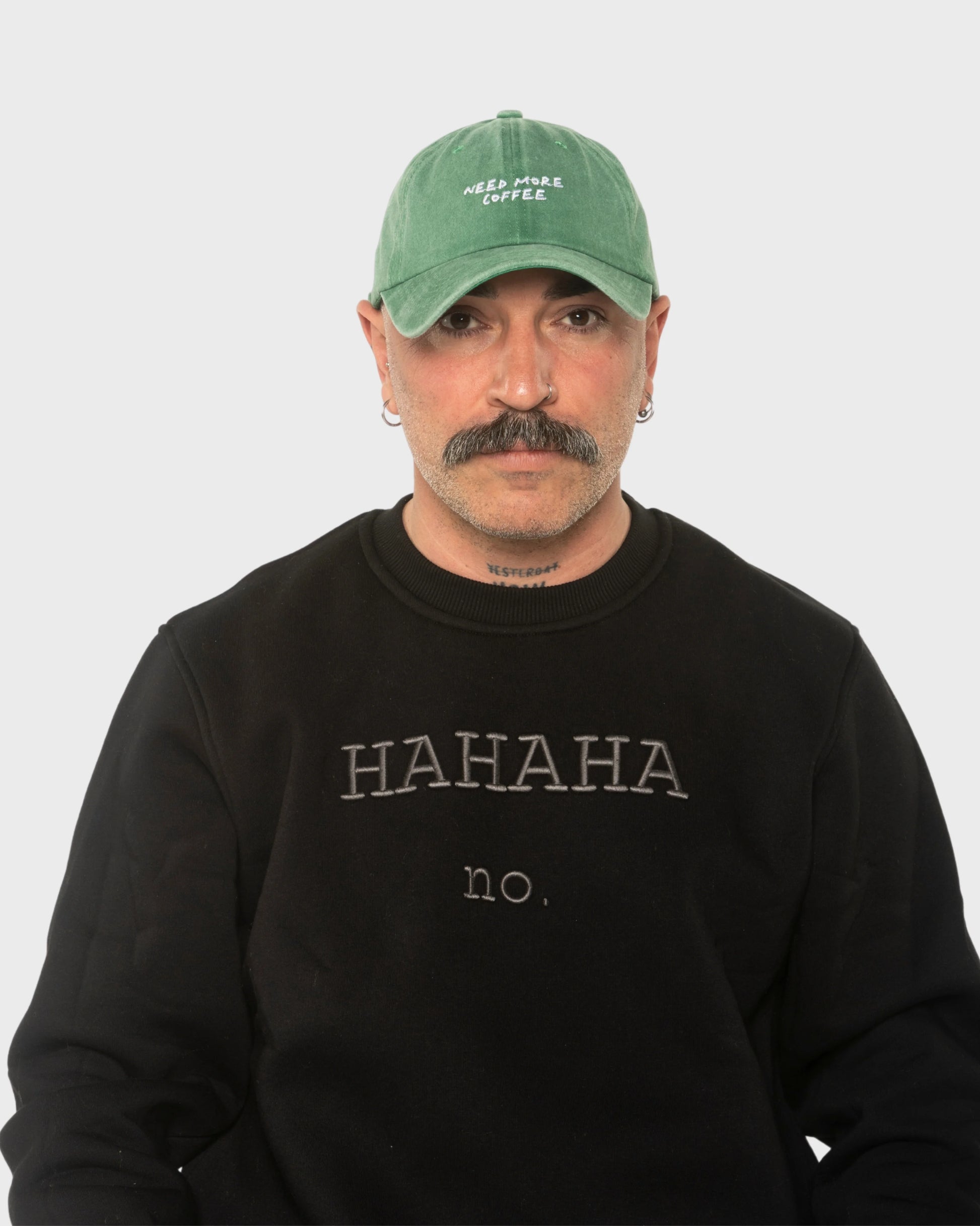 A man wearing the Need More Coffee Green Washed Cap