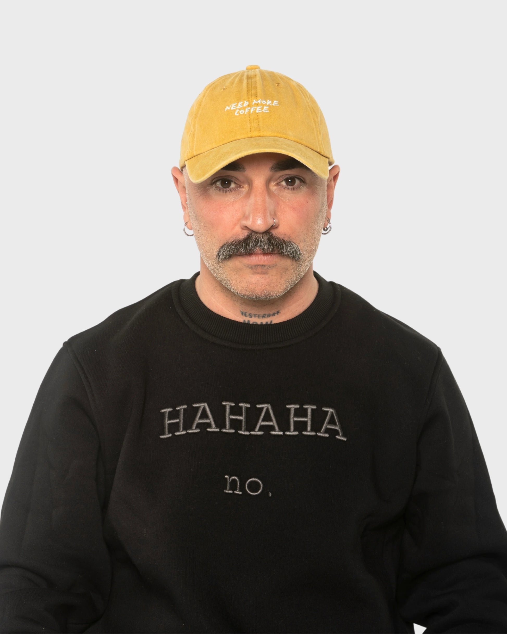 A man wearing the Need More Coffee Mustard Washed Cap