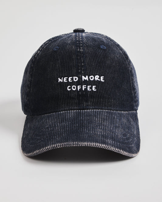 Navy corduroy cap with 'NEED MORE COFFEE' text on a light gray background