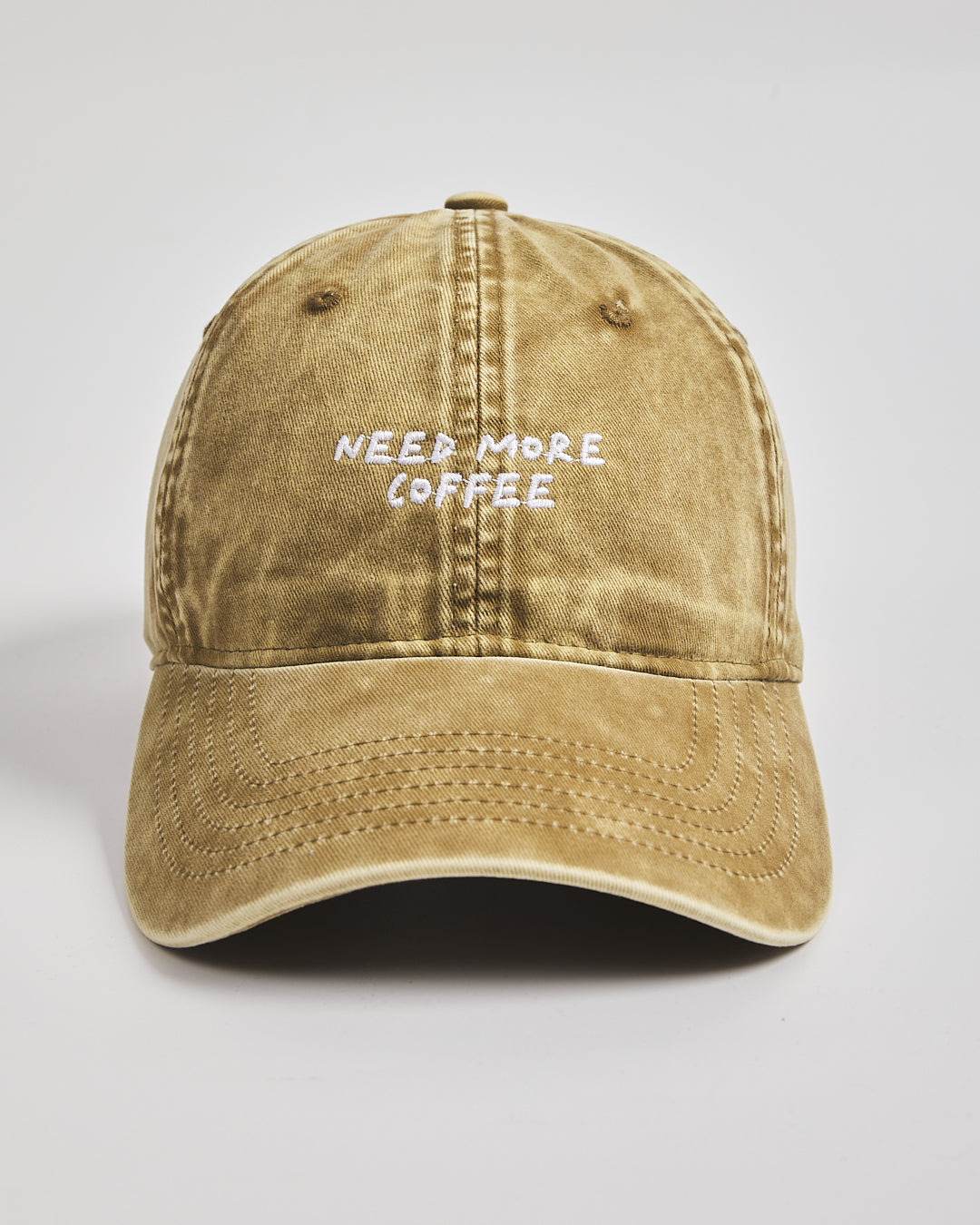 Brown cap with 'NEED MORE COFFEE' text on a light gray background
