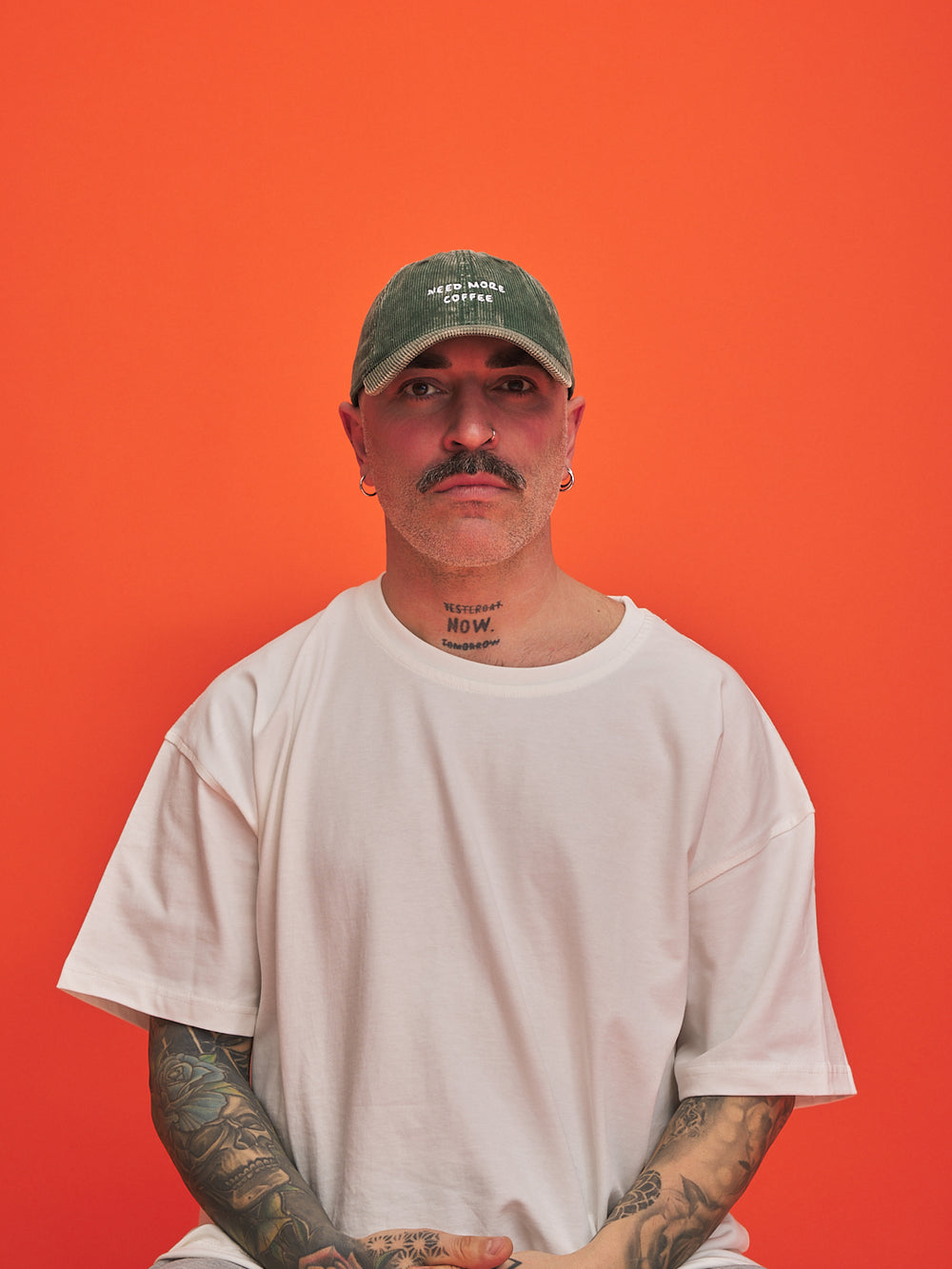 Man wearing a green cap and white t-shirt against an orange background