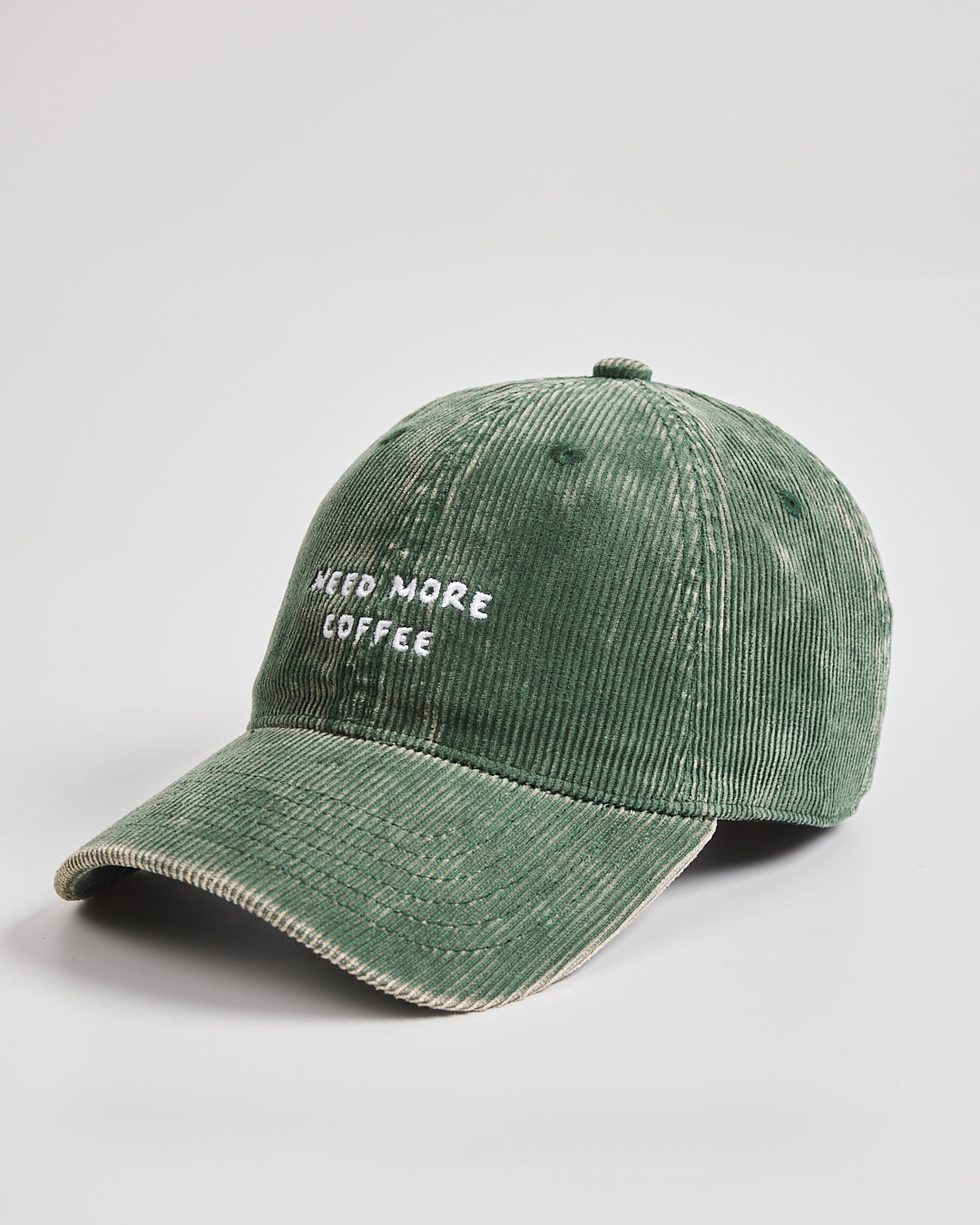 Green cap with 'Need More Coffee' text on a light gray background