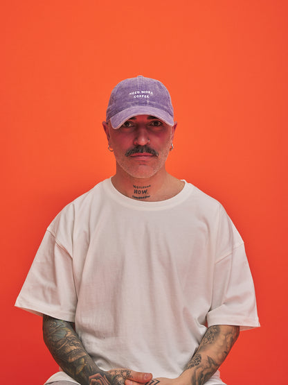 Man wearing a light purple cap and white t-shirt against an orange background