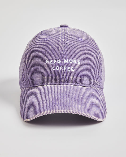 Purple corduroy cap with 'Need More Coffee' text on a light gray background