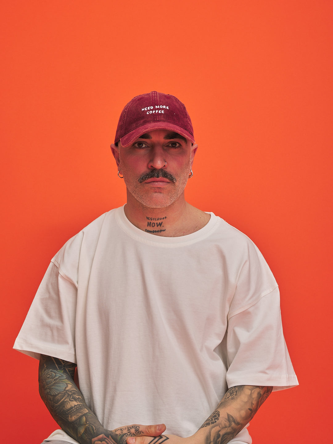 Man wearing a red cap and white t-shirt against an orange background