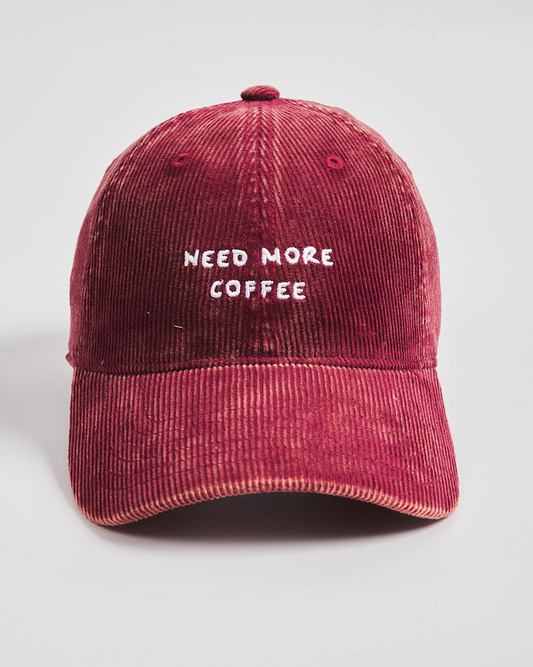 Red cap with 'NEED MORE COFFEE' text on a light gray background