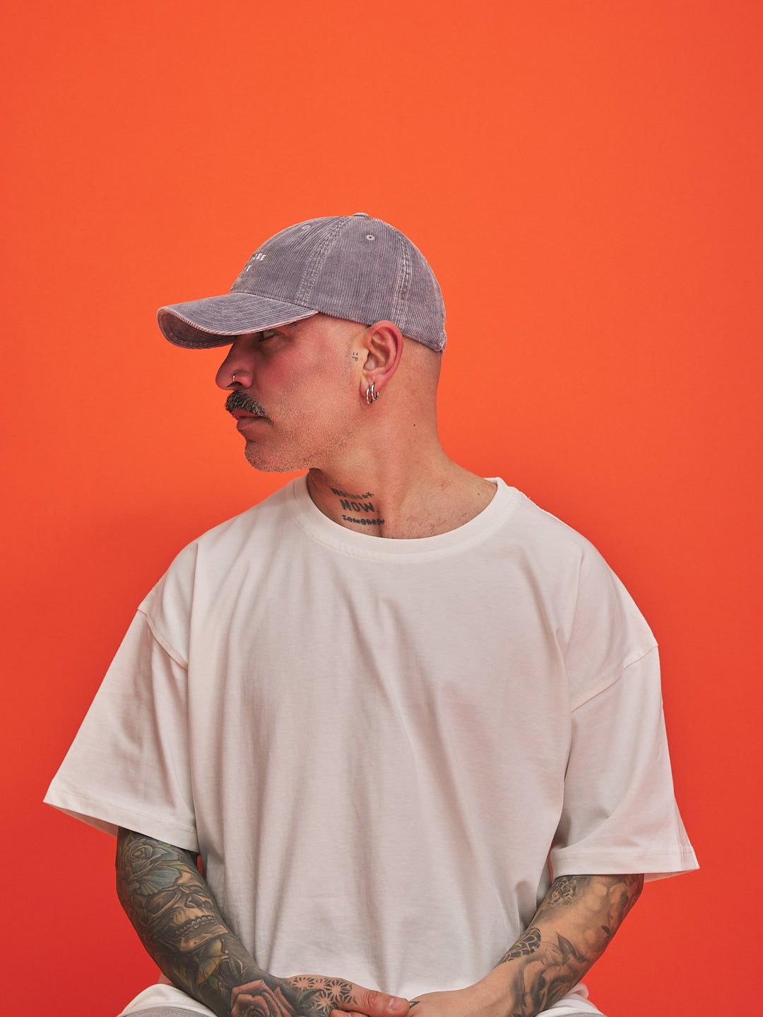 Person wearing a gray cap and white t-shirt against an orange background