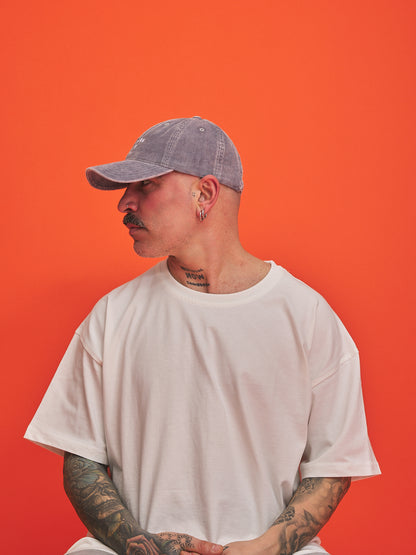 Person wearing a gray cap and white t-shirt against an orange background