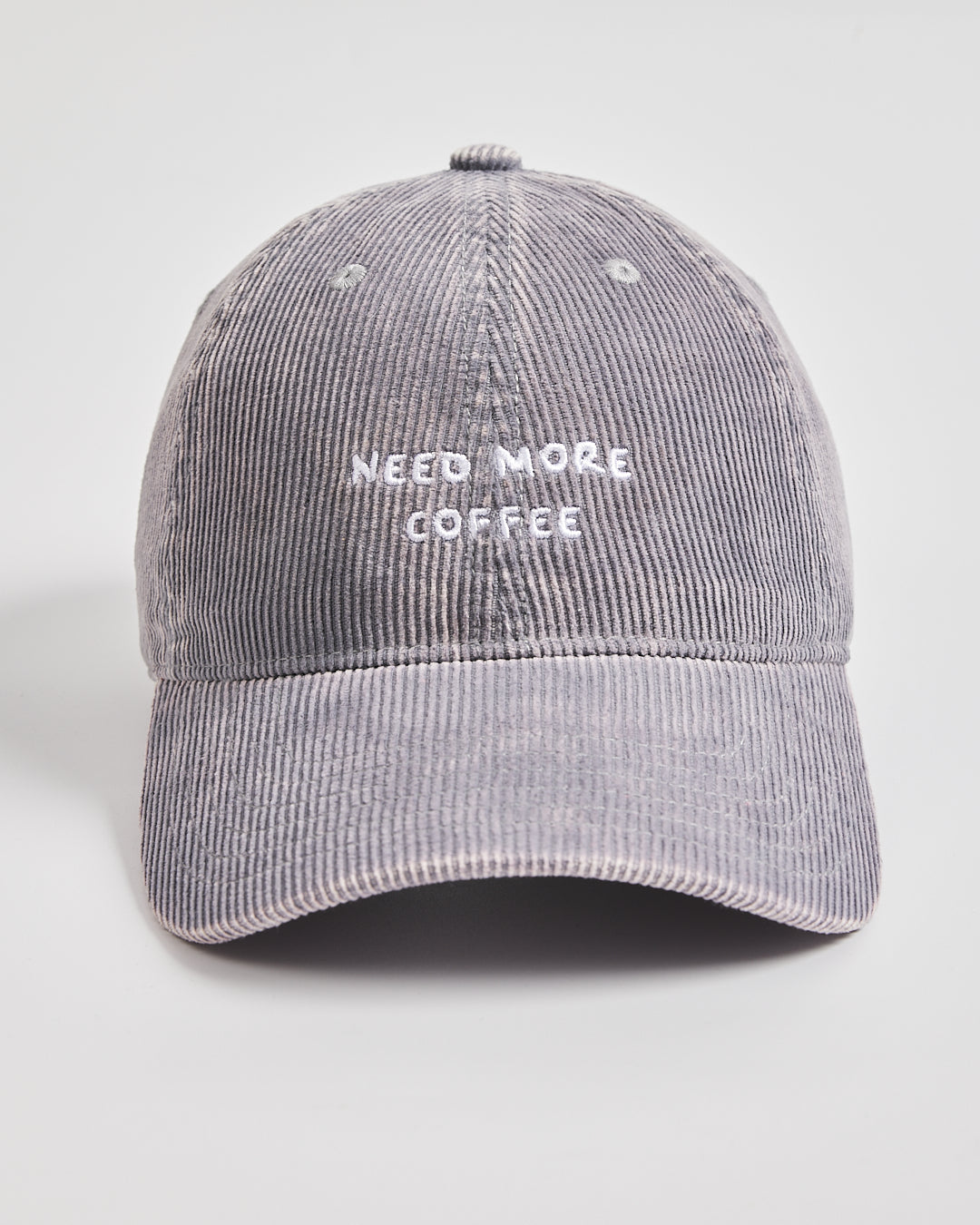 Gray corduroy cap with 'Need More Coffee' text on a light gray background