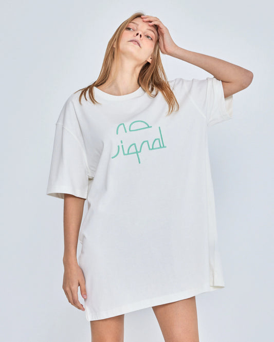 Woman wearing a white oversized t-shirt with green text on a plain background