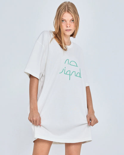 Woman wearing a white oversized t-shirt with green text on a light gray background