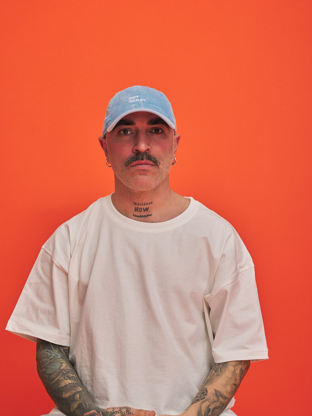 Person wearing a light blue cap and white t-shirt against an orange background