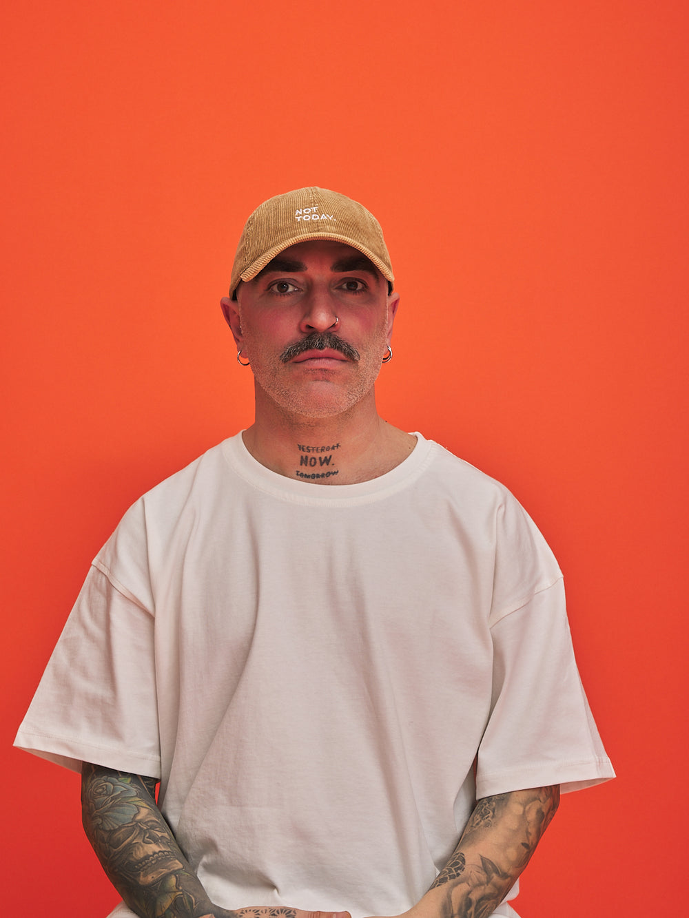 Man wearing a camel cap and white t-shirt against an orange background