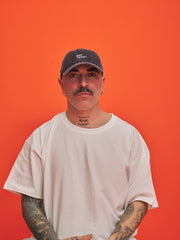 Man wearing a cap and white t-shirt against an orange background