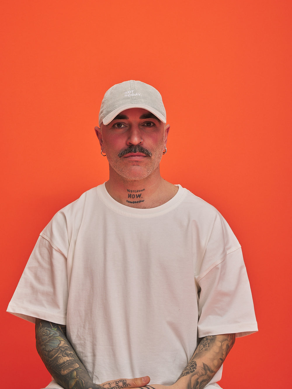 Man wearing a white cap and t-shirt against an orange background