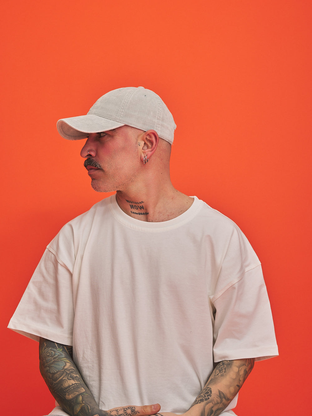 Person wearing a white cap and t-shirt against an orange background