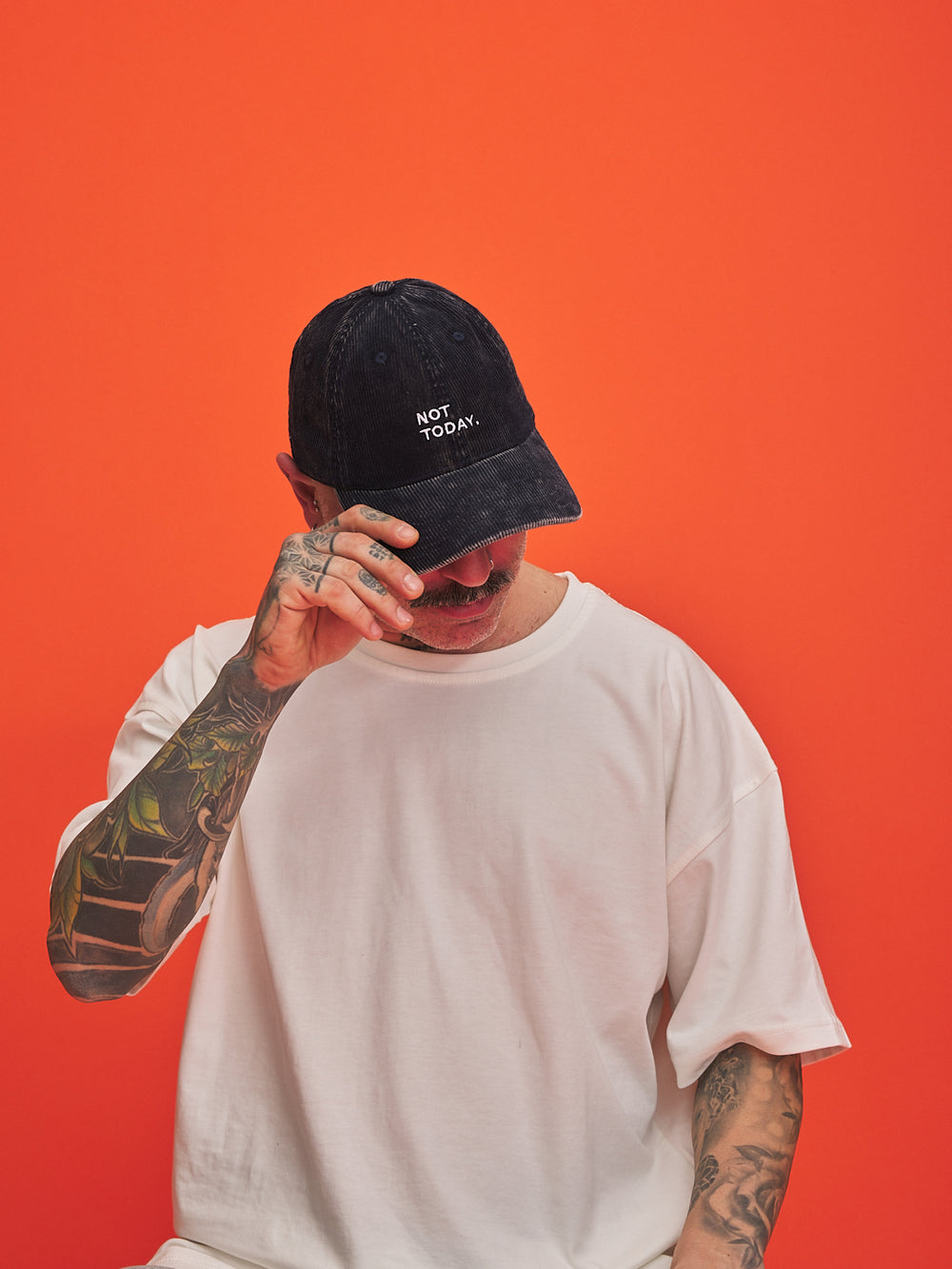 Person wearing a navy cap with 'Not Today' text on an orange background