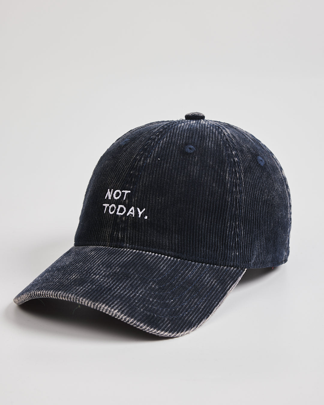 Navy cap with 'Need More Coffee' text on a light gray background