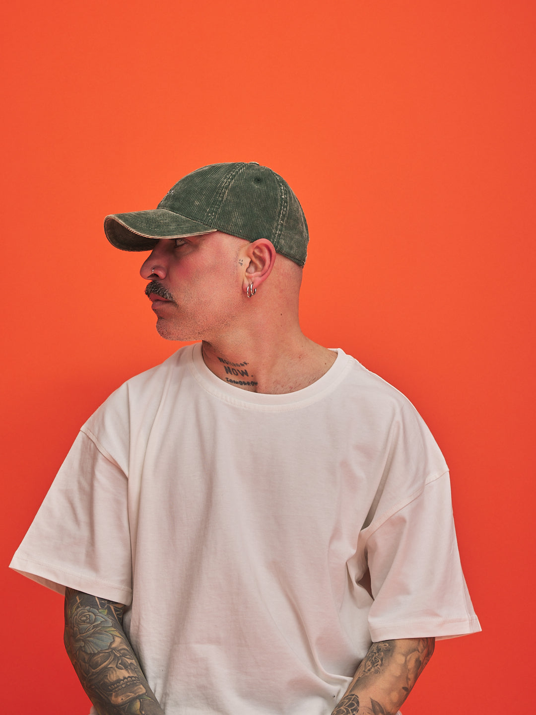Man wearing a green cap and white t-shirt against an orange background