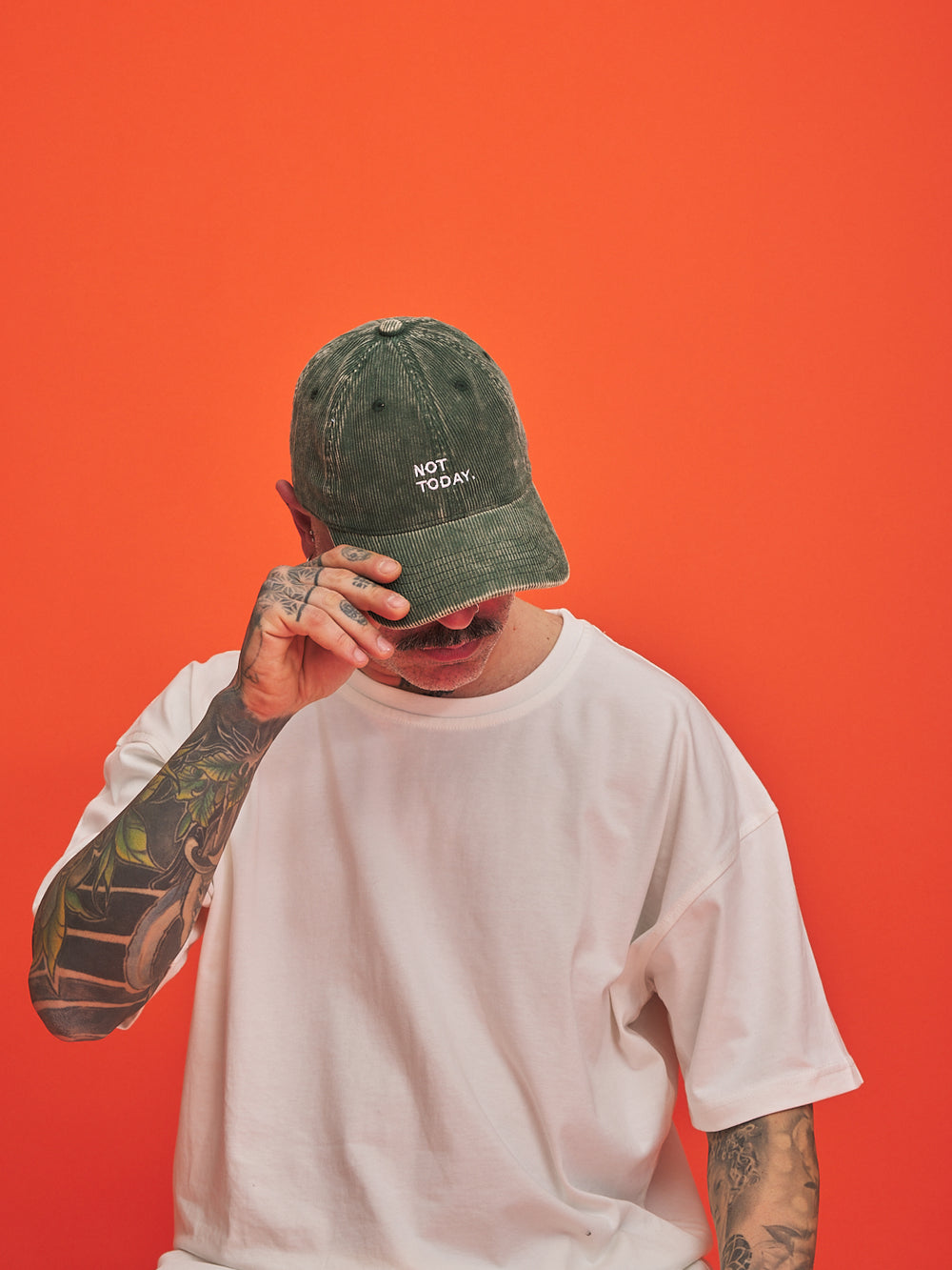 Person wearing a green cap with 'Not Today' text on an orange background