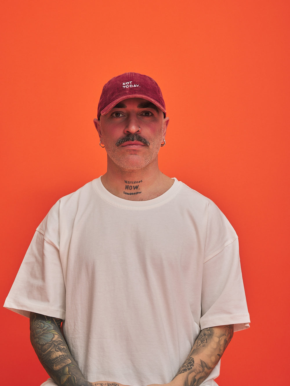 Person wearing a red cap and white t-shirt against an orange background