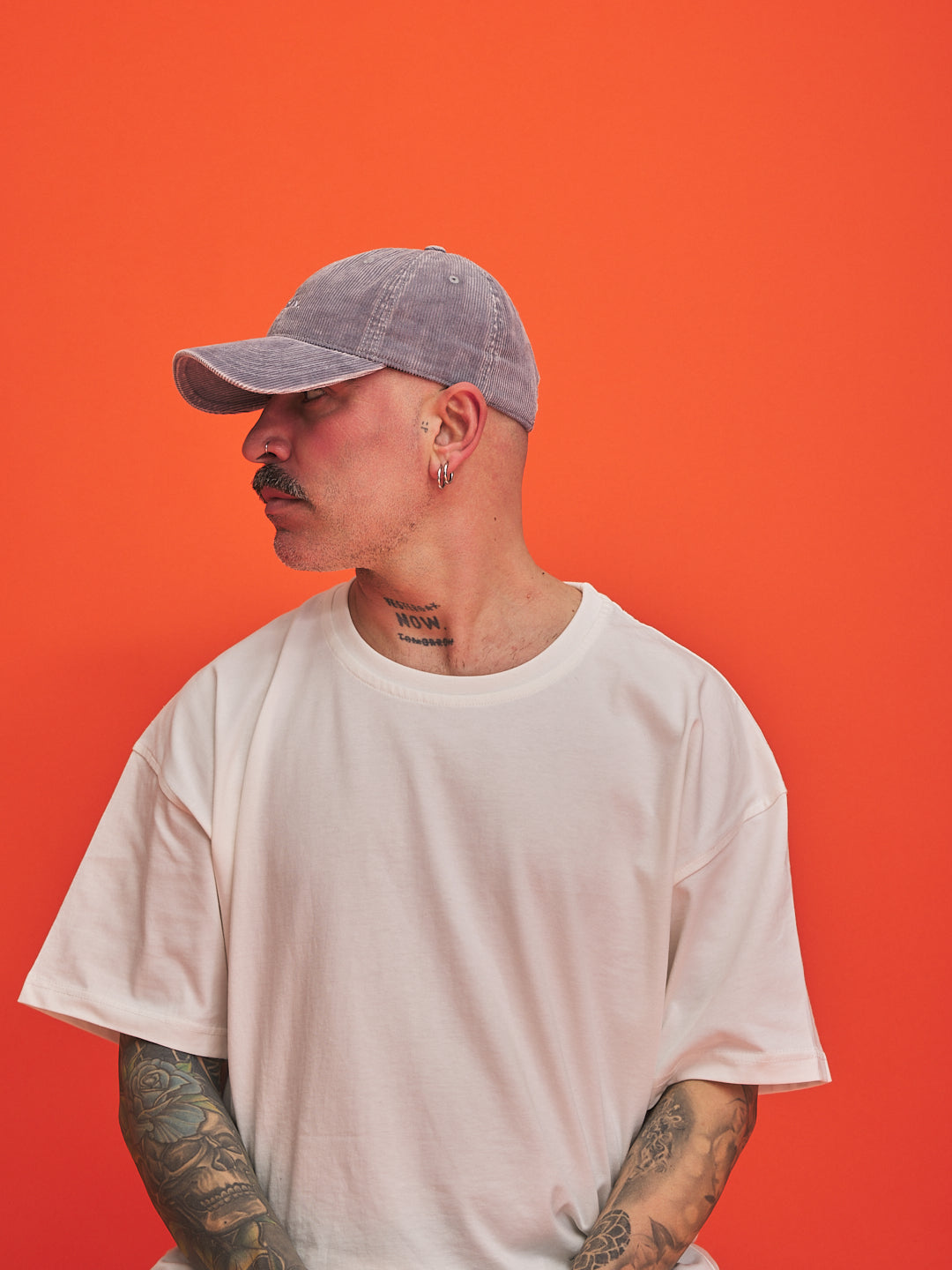 Man wearing a gray cap and white t-shirt against an orange background