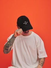 Person wearing a black cap with text on an orange background