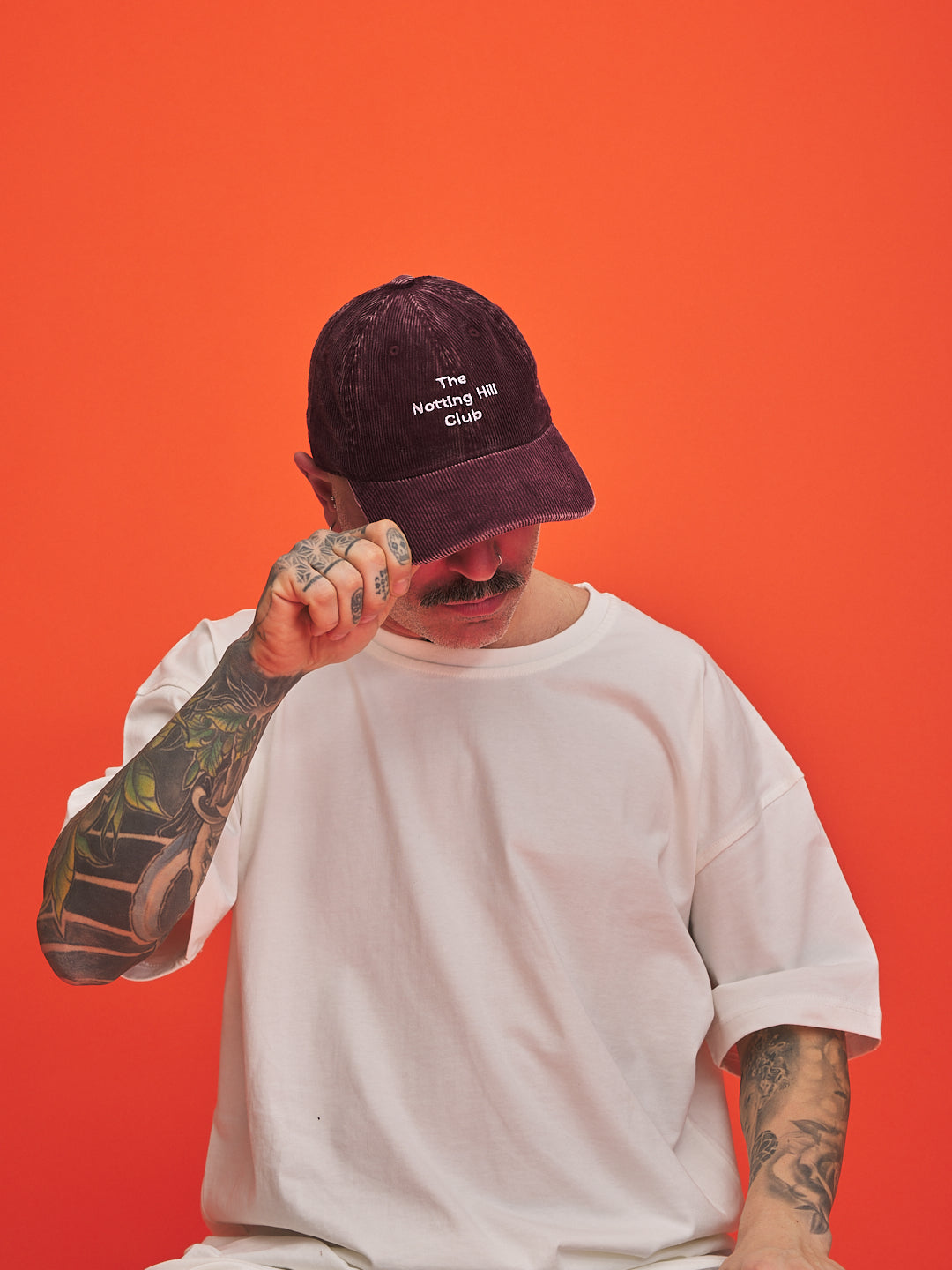 Person wearing a maroon cap with text on an orange background