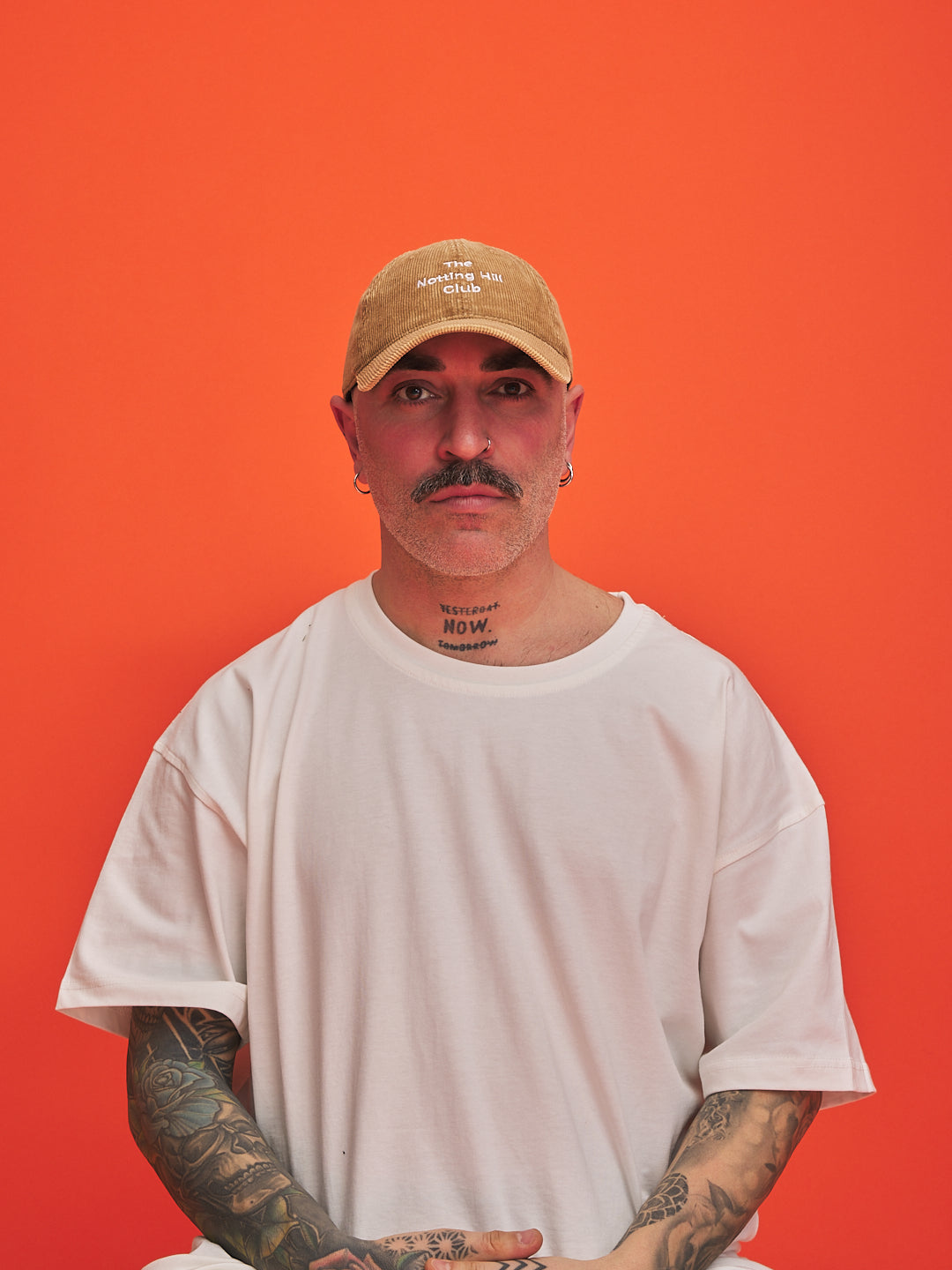 Man wearing a camel cap and white t-shirt against an orange background