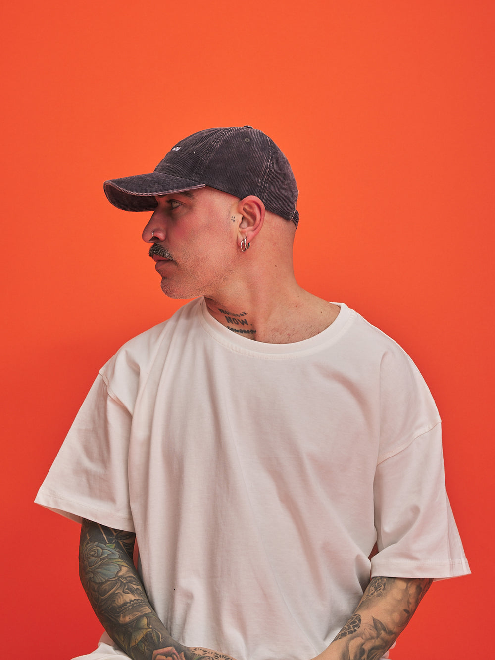 Man wearing a cap and white t-shirt against an orange background