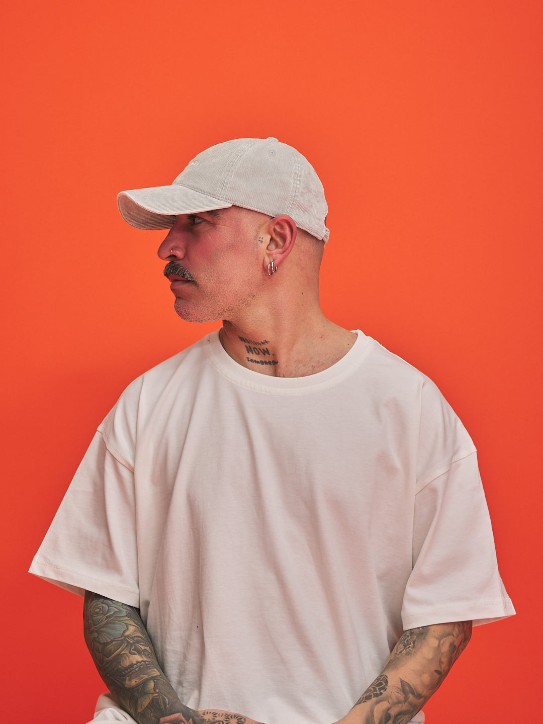 Man wearing a grey cap and t-shirt against an orange background