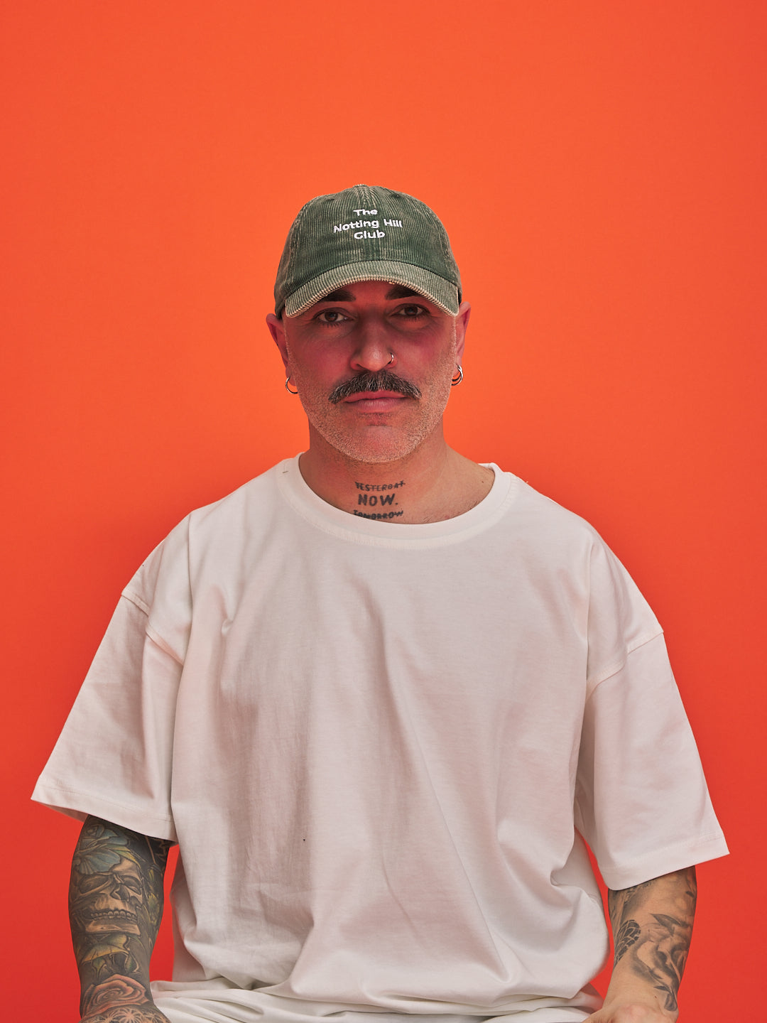 Man wearing a green cap and white t-shirt against an orange background