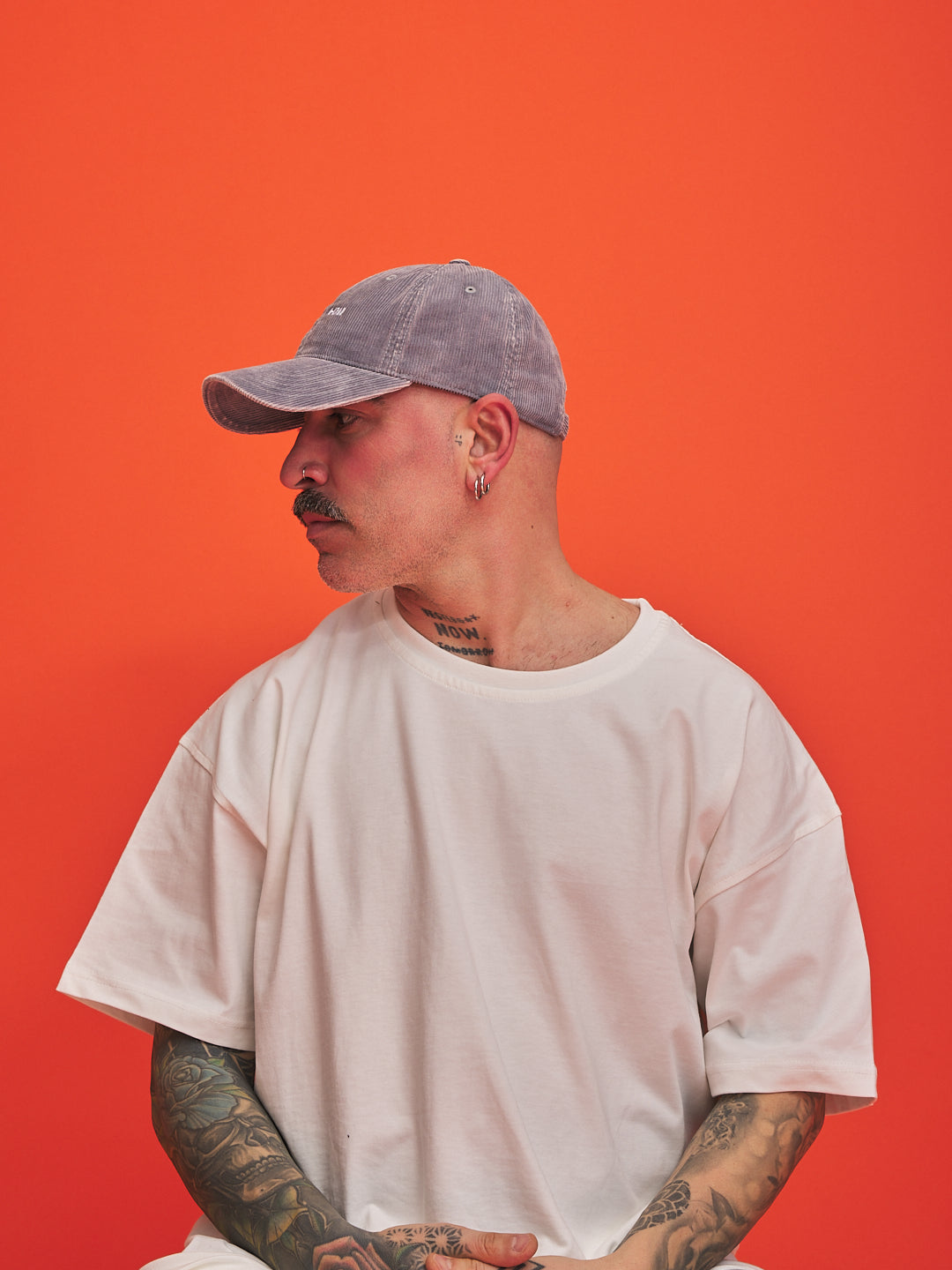 Person wearing a gray cap and white t-shirt against an orange background