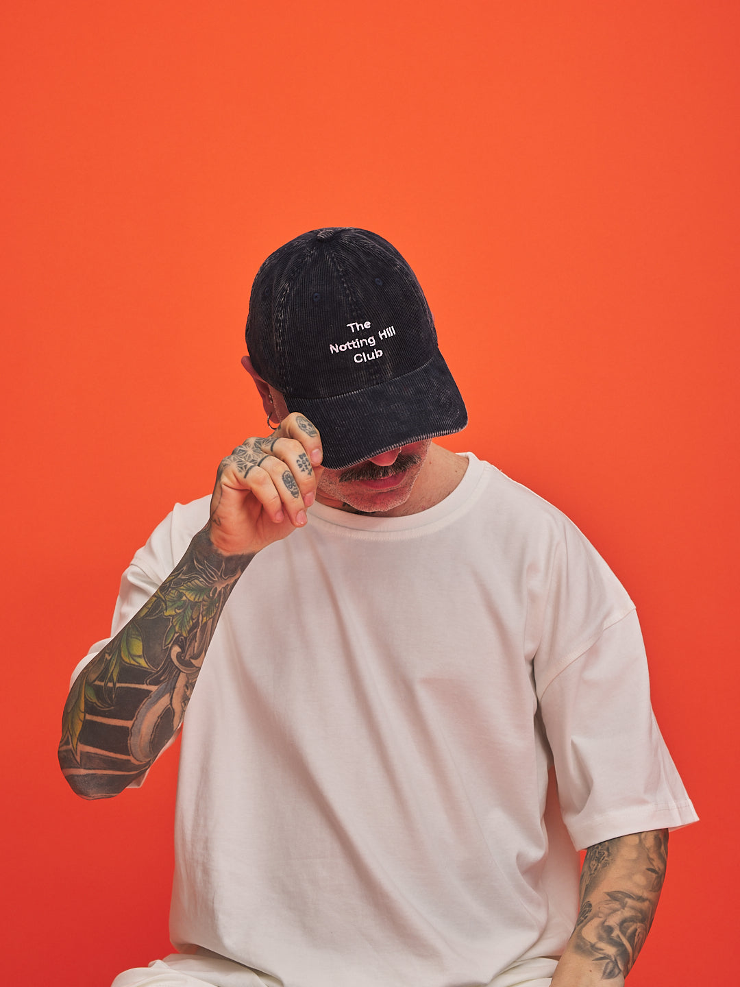 Person wearing a navy cap with text on an orange background