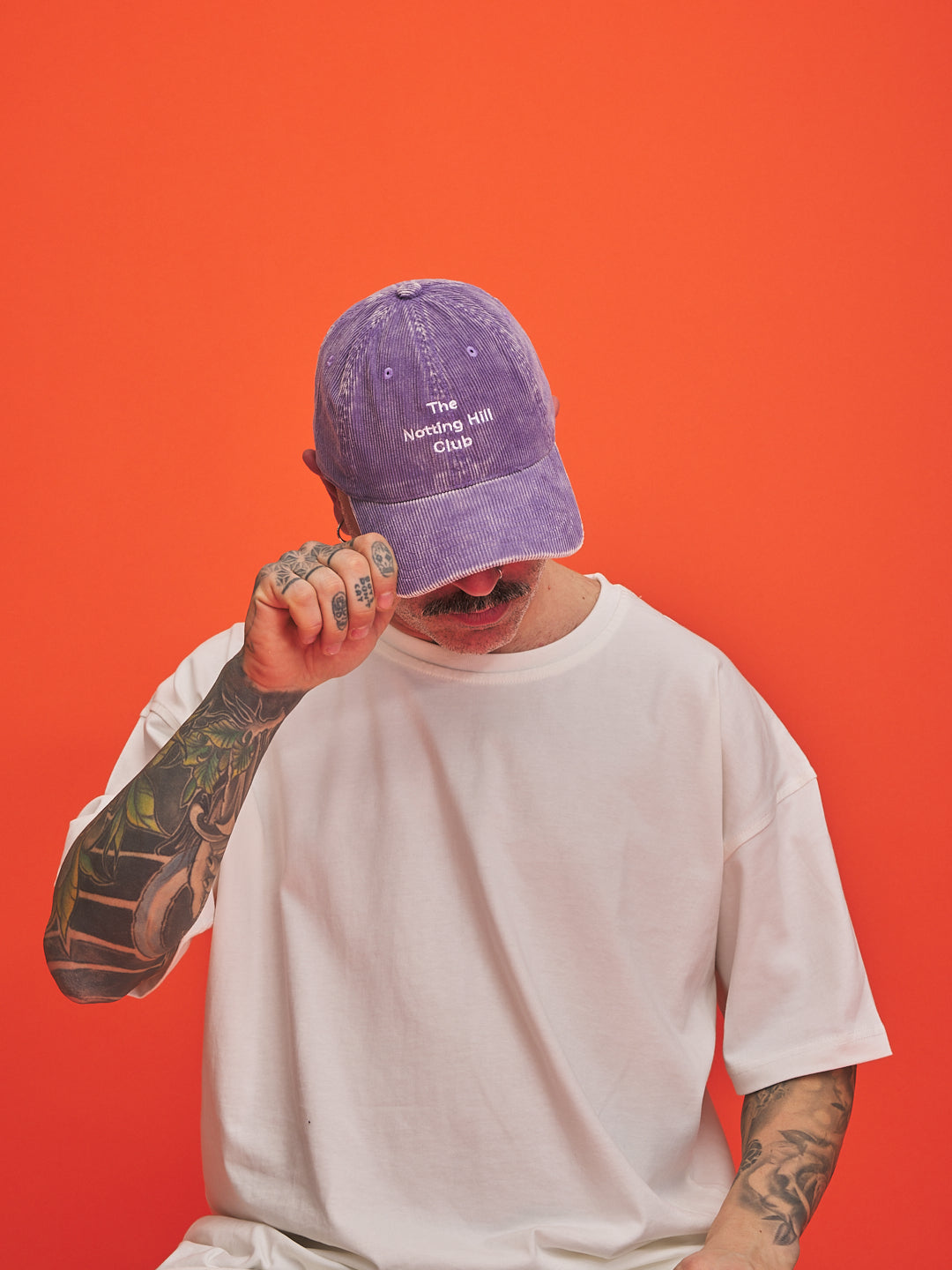 Person wearing a purple cap with text on an orange background
