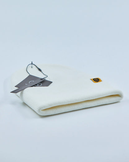 White beanie with a tag and logo on a light gray background