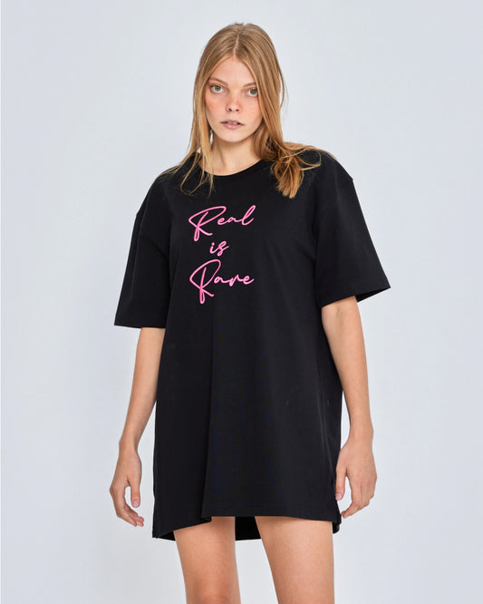 Black t-shirt with 'Real is Rare' text worn by a model on a light gray background