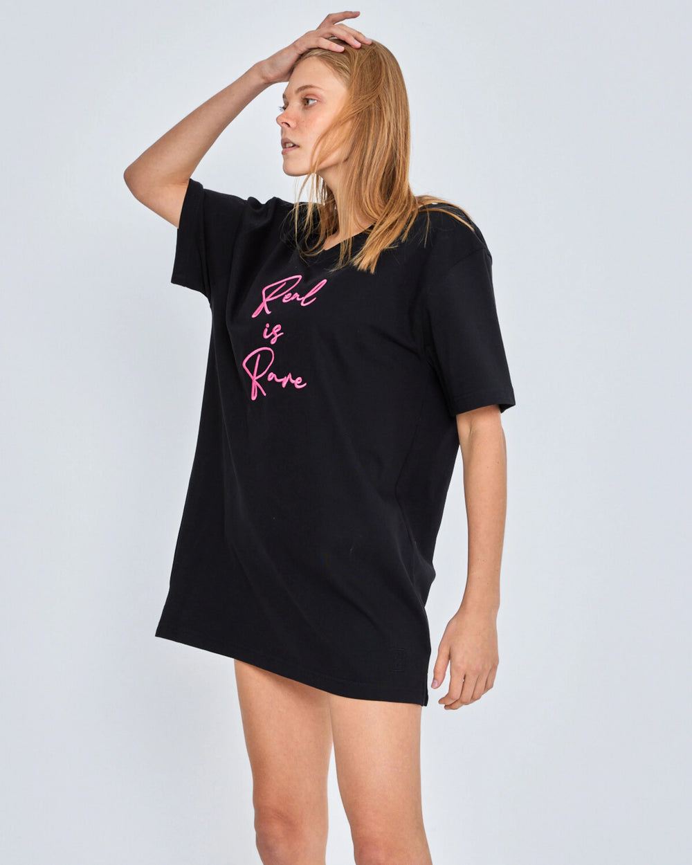 Woman wearing a black t-shirt with pink text on a white background