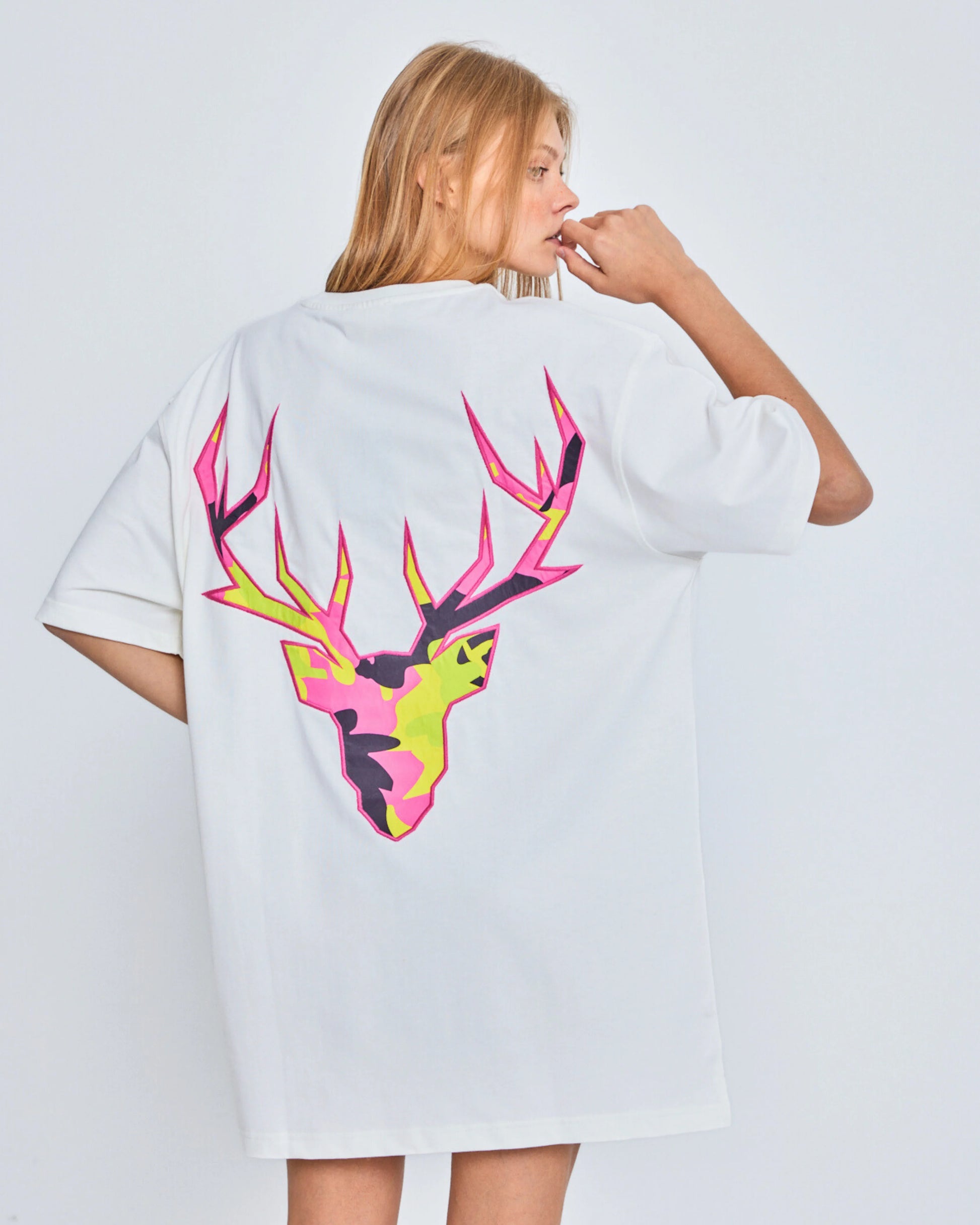 Person wearing a white t-shirt with a colorful deer graphic on the back against a plain background